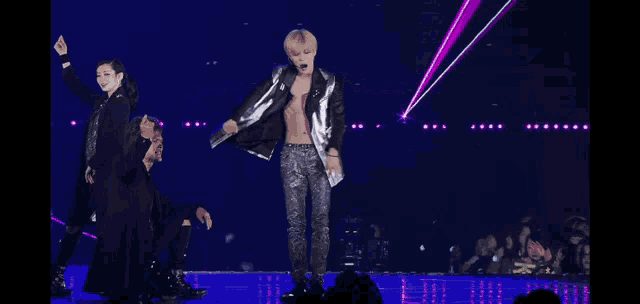 a man in a silver jacket and black pants stands on stage