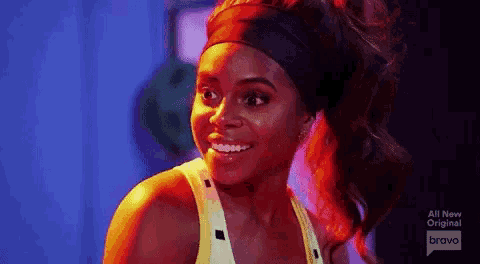 a woman in a yellow tank top and headband is smiling .