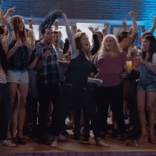 a woman in a purple shirt is dancing in a crowd