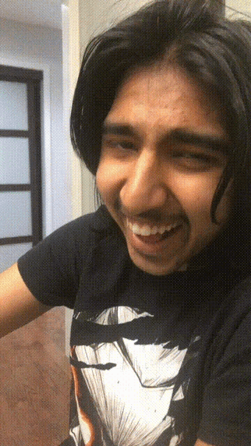 a man with long hair and a mustache is wearing a black shirt with a picture of a man 's face on it