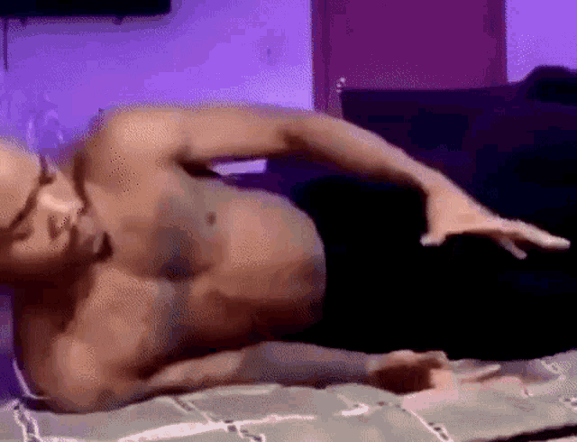 a shirtless man is laying on a bed .