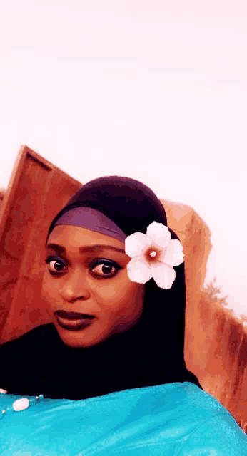 a woman wearing a hijab with a flower in her hair