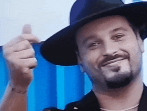 a man wearing a hat is giving a thumbs up sign