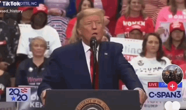 a man in a suit and tie is standing at a podium giving a speech