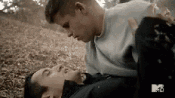 a couple of men are laying on the ground and kissing .