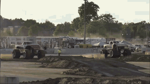 two monster trucks are racing on a dirt track