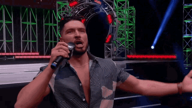 a man is singing into a microphone with his arms outstretched .