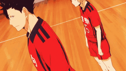 two anime characters are standing next to each other on a wooden floor .