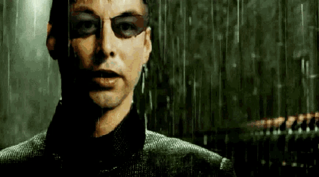 a man is wearing sunglasses and standing in the rain .