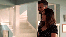 a man and a woman are standing next to each other in a room in front of stairs .