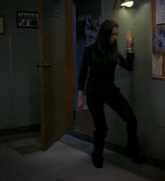 a woman in a black suit is walking through a hallway