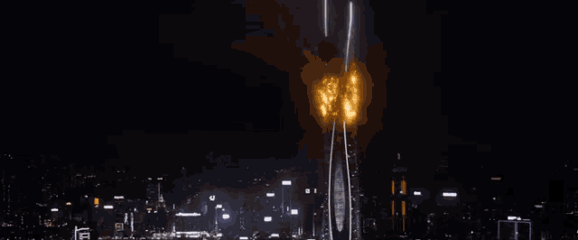 a very tall building is on fire in the middle of the night .