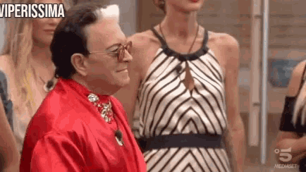 a man in a red robe is standing next to a woman in a striped dress and smiling .