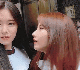 two women with long hair are standing next to each other .