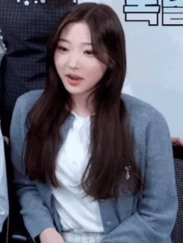 a woman with long hair is wearing a blue cardigan