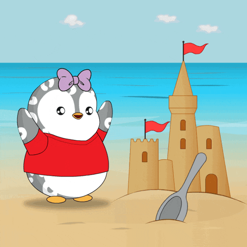 a penguin wearing a red shirt is standing in front of a sand castle and a shovel