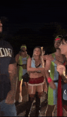 a group of people dressed in costumes are standing around a man wearing a shirt that says liar .