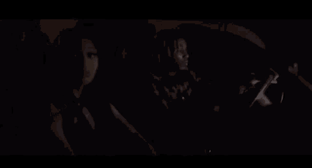 a close up of a woman 's face in the dark with a hand behind her ear .