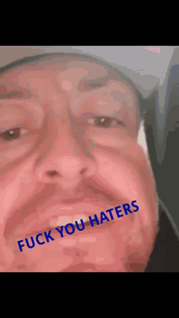 a close up of a man 's face with the words fuck you haters written on his face