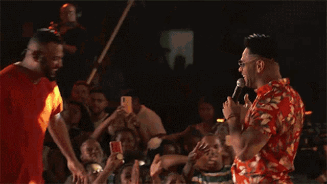 two men are singing into microphones in front of a crowd of people
