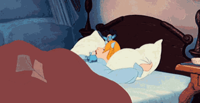 a cartoon girl is sleeping in a bed with a stuffed animal on her head .