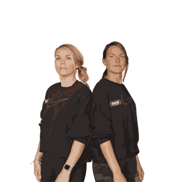 two women wearing nike shirts are standing back to back with their arms outstretched