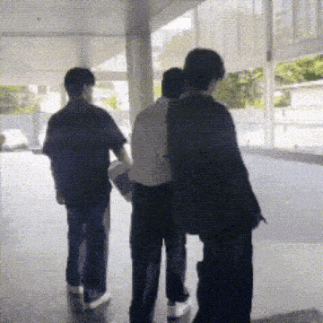 a group of people are walking down a hallway and one of them is carrying a skateboard .