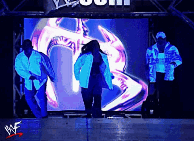 a group of people are dancing in front of a large screen that says wwe
