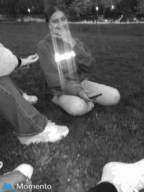 a black and white photo of people sitting on the grass with the word momento on the bottom left