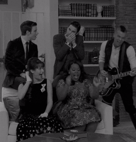 a black and white photo of a group of people with one man holding a guitar