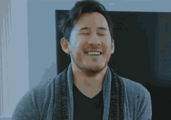 a man with a beard and a scarf around his neck is smiling .