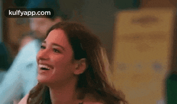 a woman is smiling and laughing while sitting in a room .