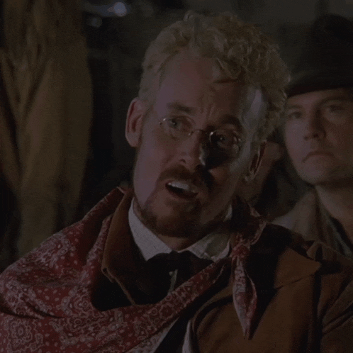 a man with glasses and a bandana around his neck looks angry