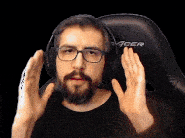 a man with glasses and a beard is wearing a black acer gaming chair