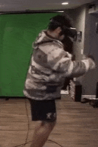 a man wearing a virtual reality headset is standing on one leg in a room .