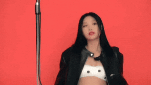 a woman is wearing a black leather jacket and a white polka dot bra .