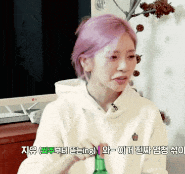 a woman with purple hair is holding a bottle in front of an lg computer monitor