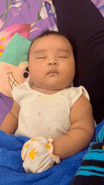 a baby is sleeping on a blue blanket with a bunny glove that says bunny on it