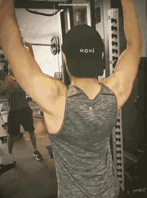 a man wearing a tank top and a black mone hat