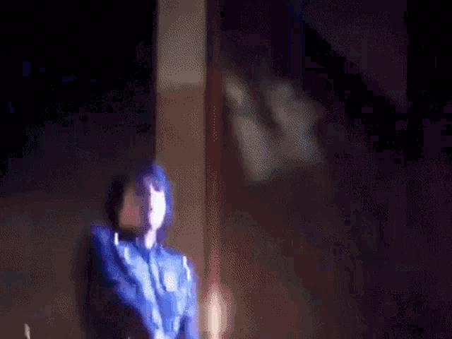 a blurry picture of a person standing in front of a fire in the dark .