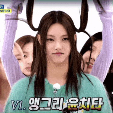 a girl in a green sweater with korean writing on the bottom right