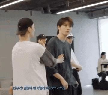 a group of young men are standing next to each other in a room and talking .
