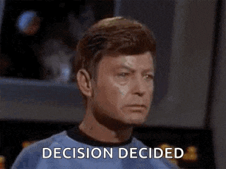 a man in a green shirt is sitting at a table with the words `` decision decided '' on his face .