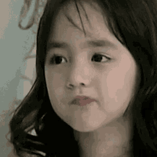 a little girl is making a funny face while looking at the camera .
