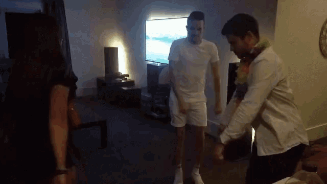 a group of people are dancing in a living room with a tv in the background