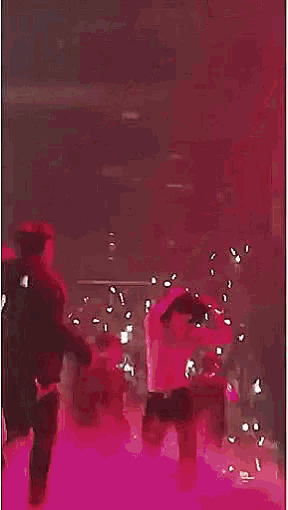 a man without a shirt is dancing on a stage in a red shirt .
