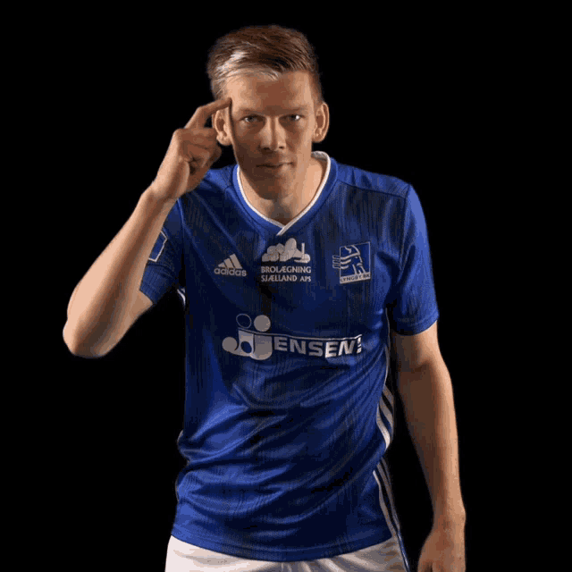a man wearing a blue adidas jersey points to his forehead