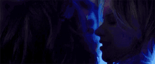 a man and a woman are kissing in a dark room in a club .