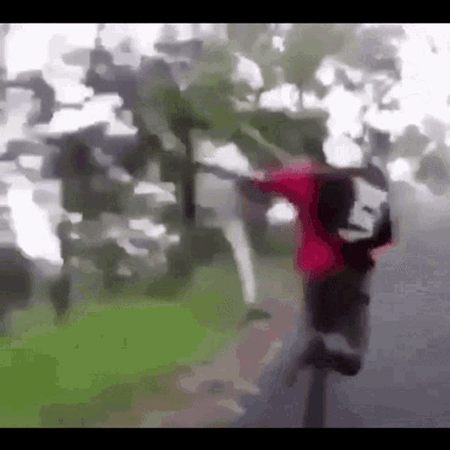 a blurry picture of a person in a red shirt walking down a sidewalk .