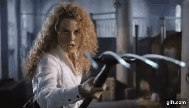 a woman with curly hair is holding a large hammer in her hand .